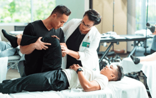 A patient on a table while two people work on his knee response.